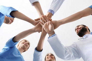 Photo of Team of medical doctors putting hands together on white background, closeup. Unity concept