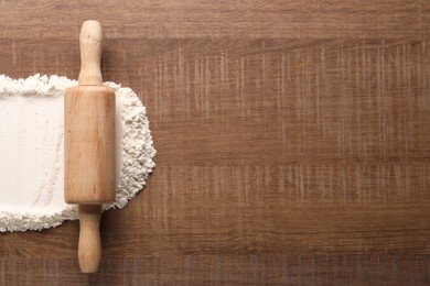 Photo of Flour and rolling pin on wooden table, top view. Space for text