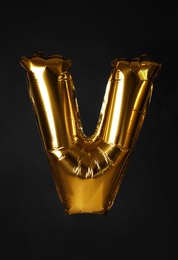 Photo of Golden letter V balloon on black background