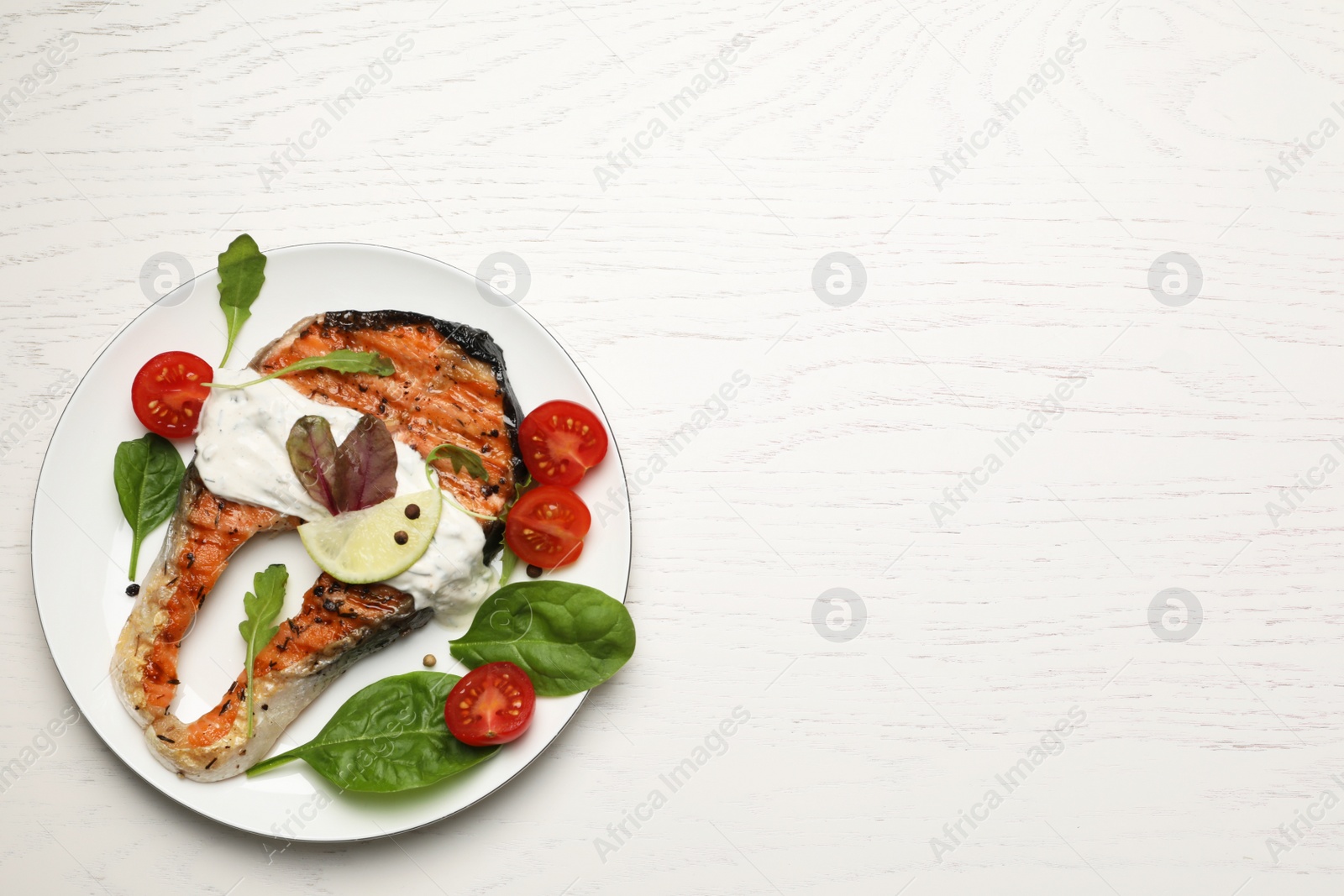 Photo of Tasty salmon steak served on white wooden table, top view. Space for text