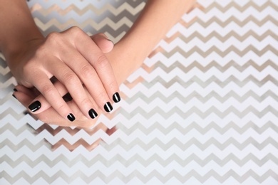 Photo of Woman showing black manicure on shining background, closeup with space for text. Nail polish trends