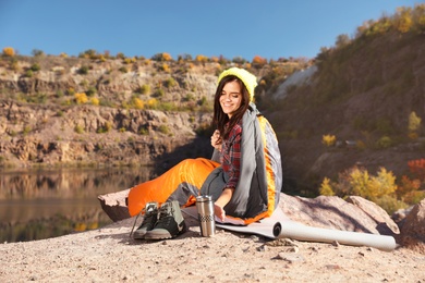 Female camper with thermos in sleeping bag outdoors