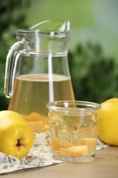 Photo of Delicious quince drink and fresh fruits on wooden table against blurred background