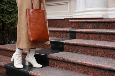 Photo of Woman in stylish leather shoes with bag on stairs outdoors, closeup