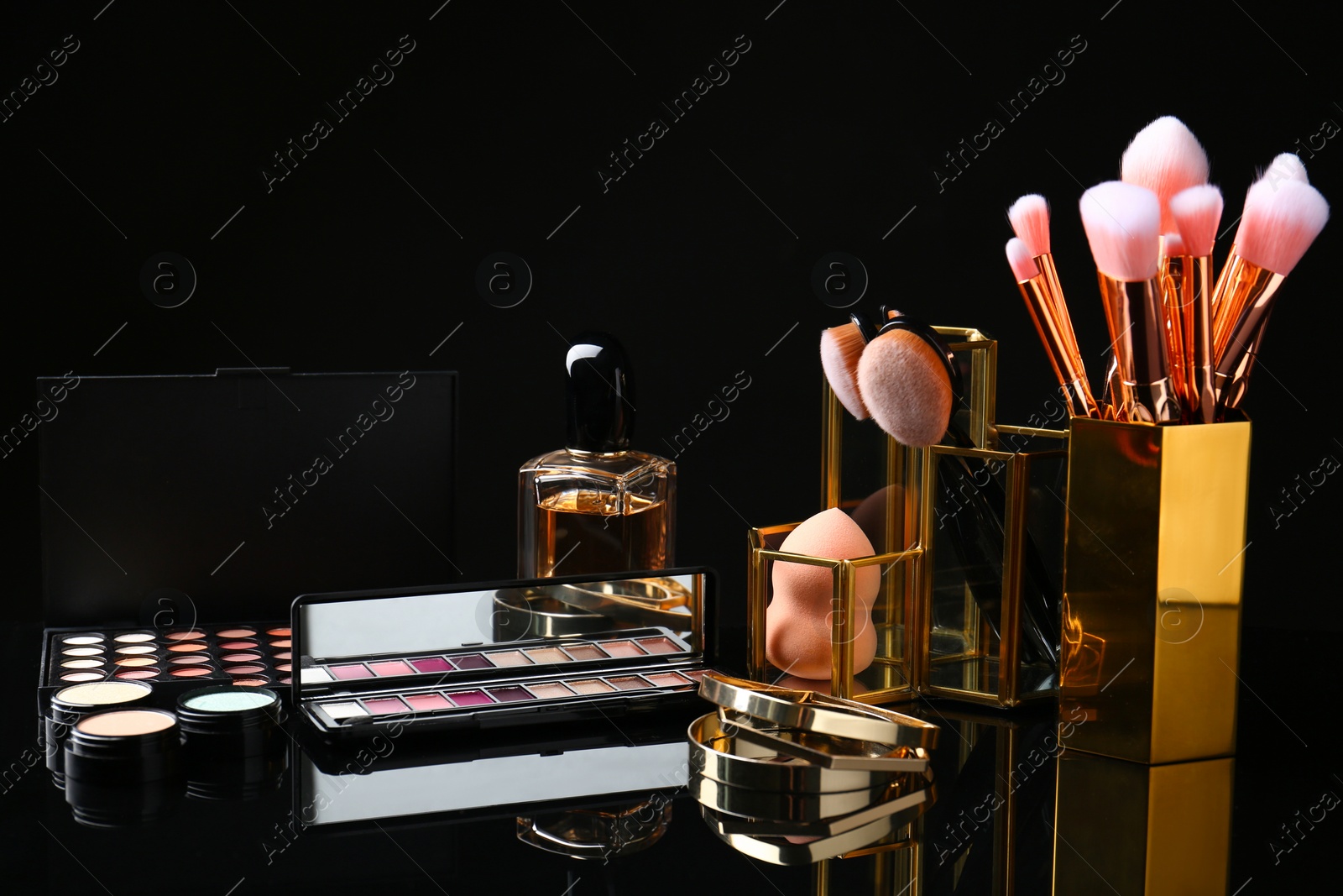 Photo of Set of makeup products and brushes on dark background