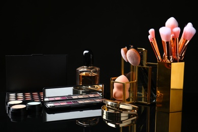 Photo of Set of makeup products and brushes on dark background