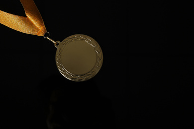 Photo of Gold medal on black background, top view. Space for design