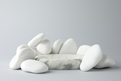 Photo of Presentation for product. Stone podium and pebbles on light grey background. Space for text