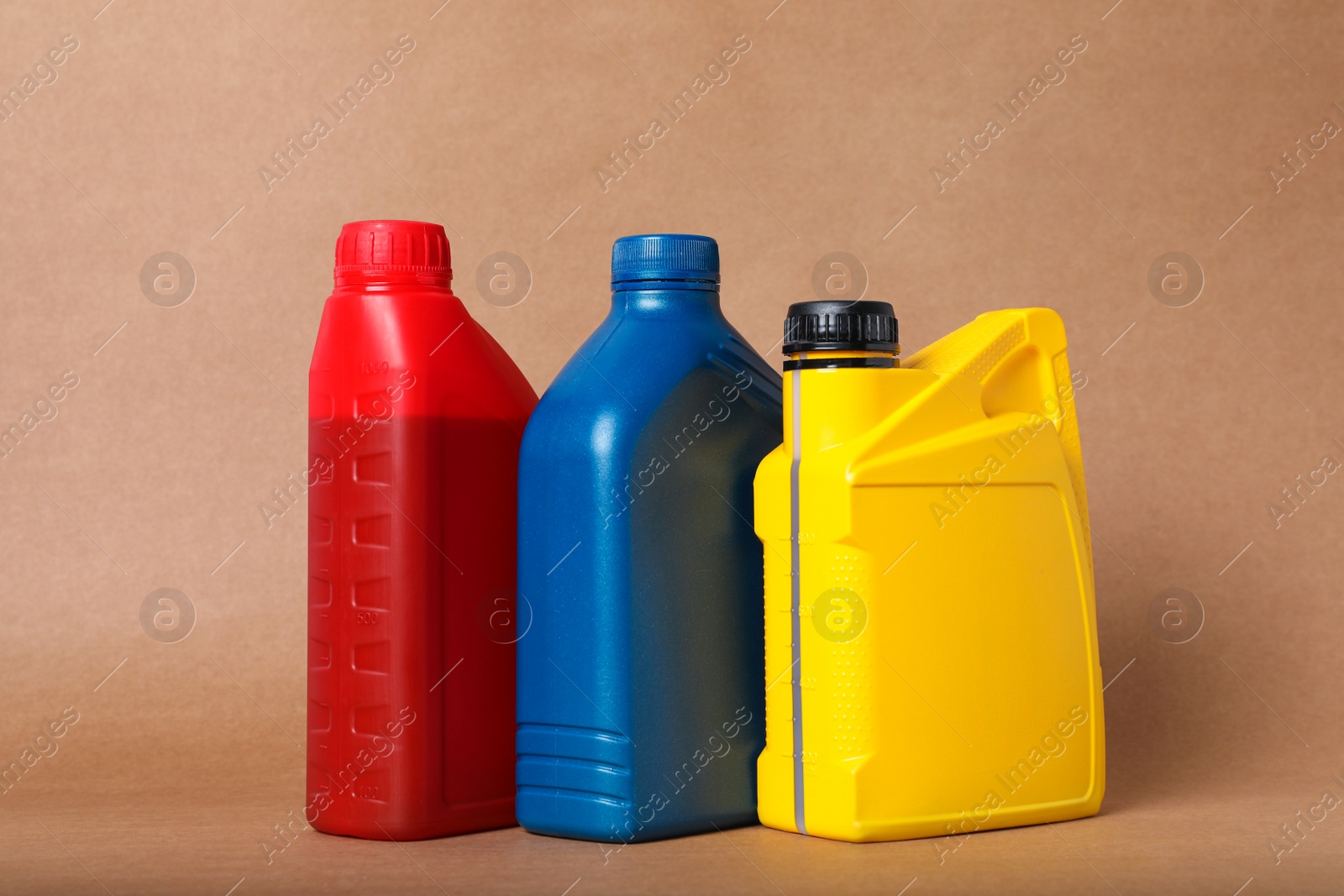 Photo of Motor oil in different canisters on light brown background