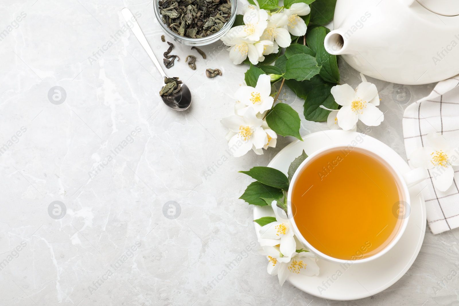 Photo of Flat lay composition with tea and fresh jasmine flowers on light grey marble table. Space for text