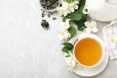 Photo of Flat lay composition with tea and fresh jasmine flowers on light grey marble table. Space for text