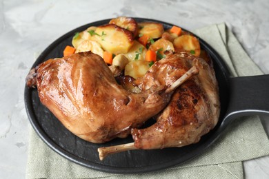 Photo of Tasty cooked rabbit meat with vegetables on light grey table, closeup