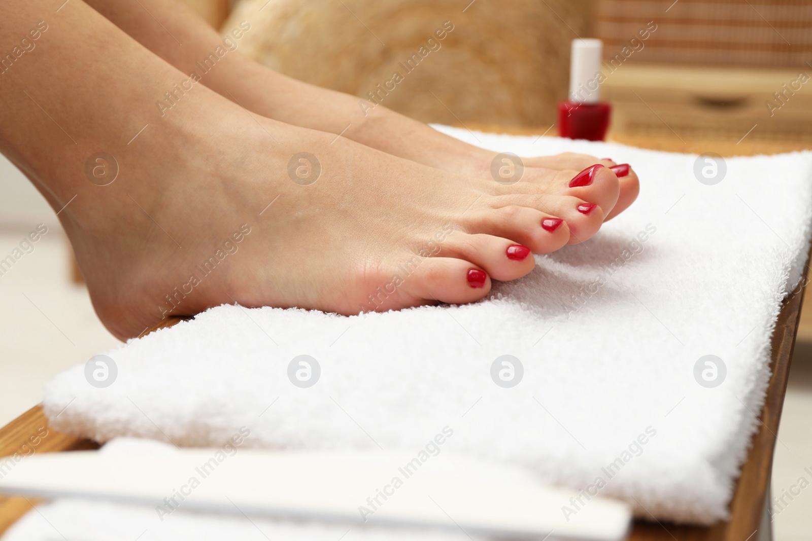 Photo of Woman with stylish red toenails after pedicure procedure on white terry towel indoors, closeup