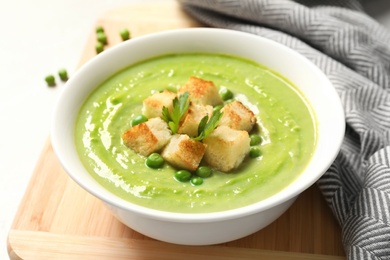 Fresh vegetable detox soup made of green peas with croutons in dish served on table