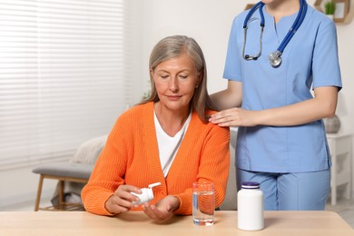 Photo of Senior woman with bottle of pills and young healthcare worker indoors