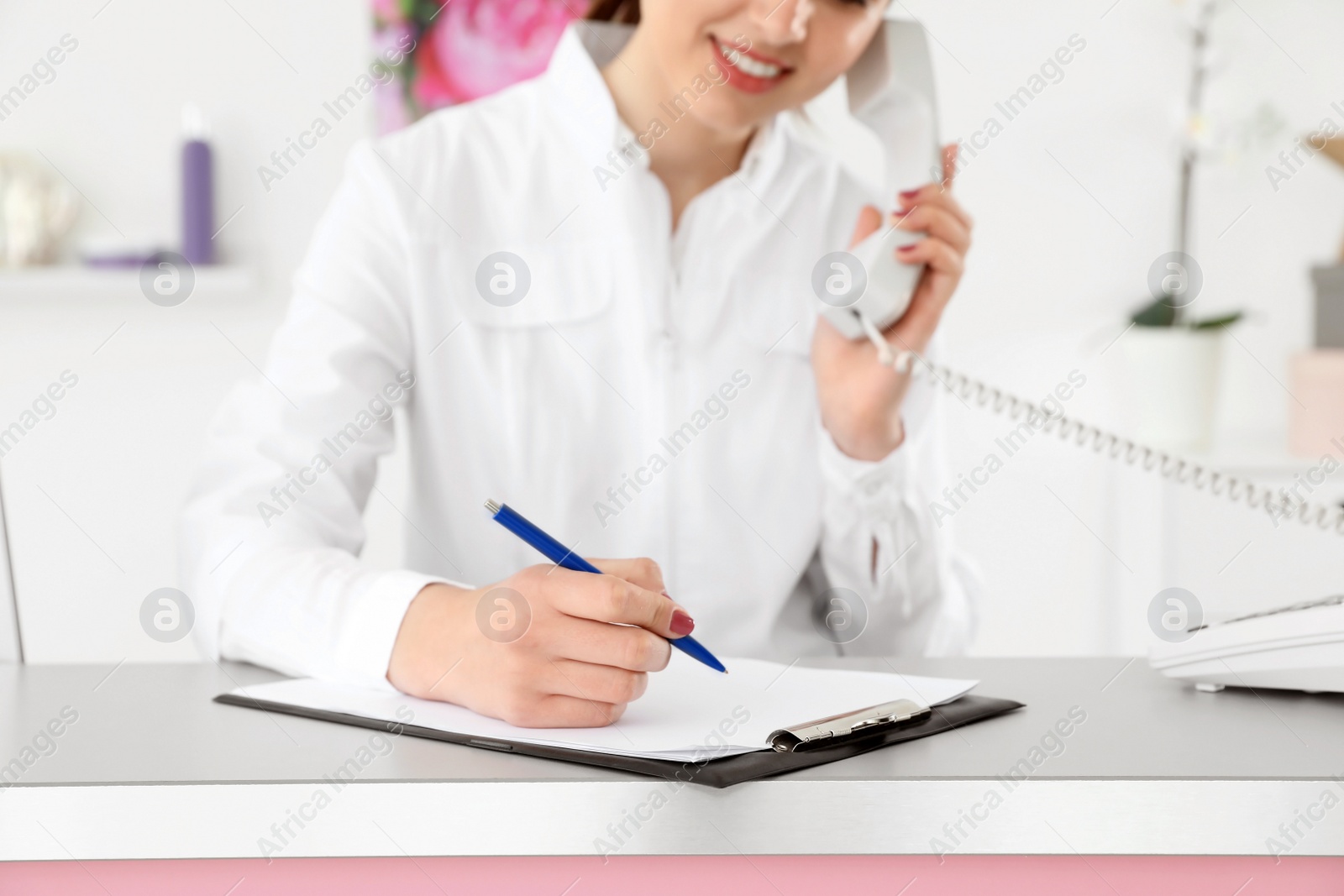 Photo of Beauty salon receptionist talking on phone at desk