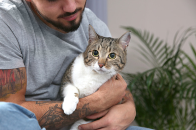 Photo of Man with tabby cat near window indoors, closeup. Friendly pet