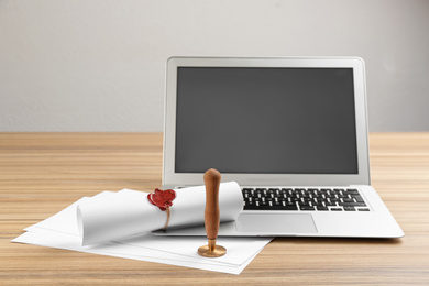 Photo of Notary's public pen and sealed document near laptop on wooden table