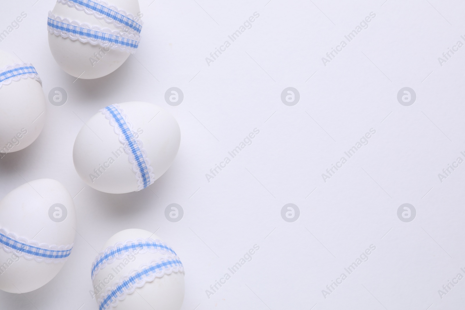Photo of Festively decorated Easter eggs on white background, flat lay. Space for text