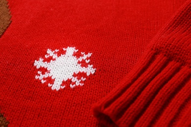 Photo of Warm red Christmas sweater with snowflake as background, closeup view