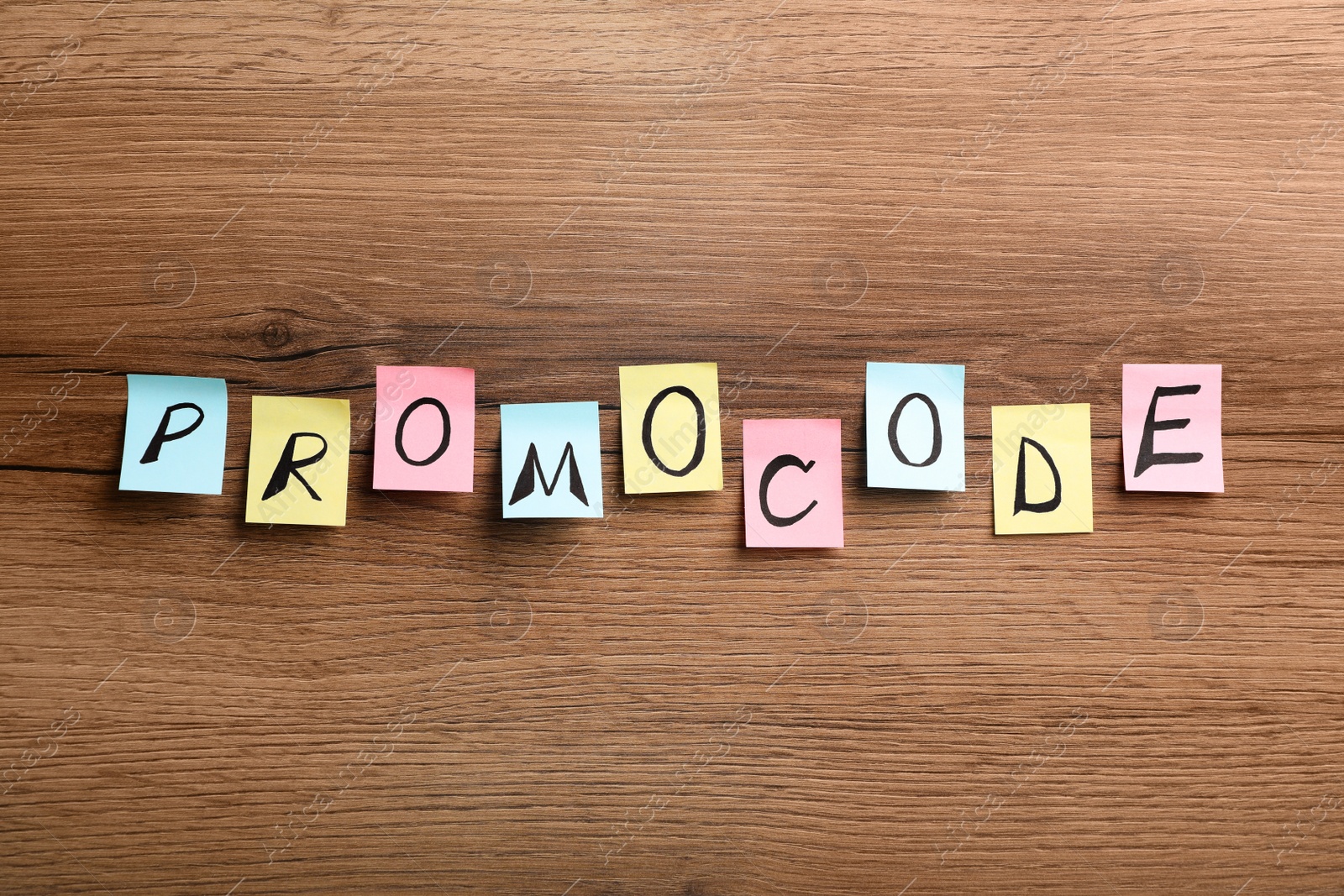 Photo of Word Promocode made of colorful paper notes with letters on wooden table, flat lay