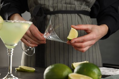 Photo of Woman making delicious Margarita cocktail at grey table, closeup
