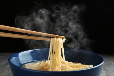 Eating noodle dish with chopsticks against black background