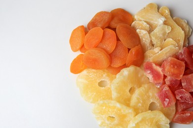 Photo of Pile of different dried fruits on white background, top view. Space for text