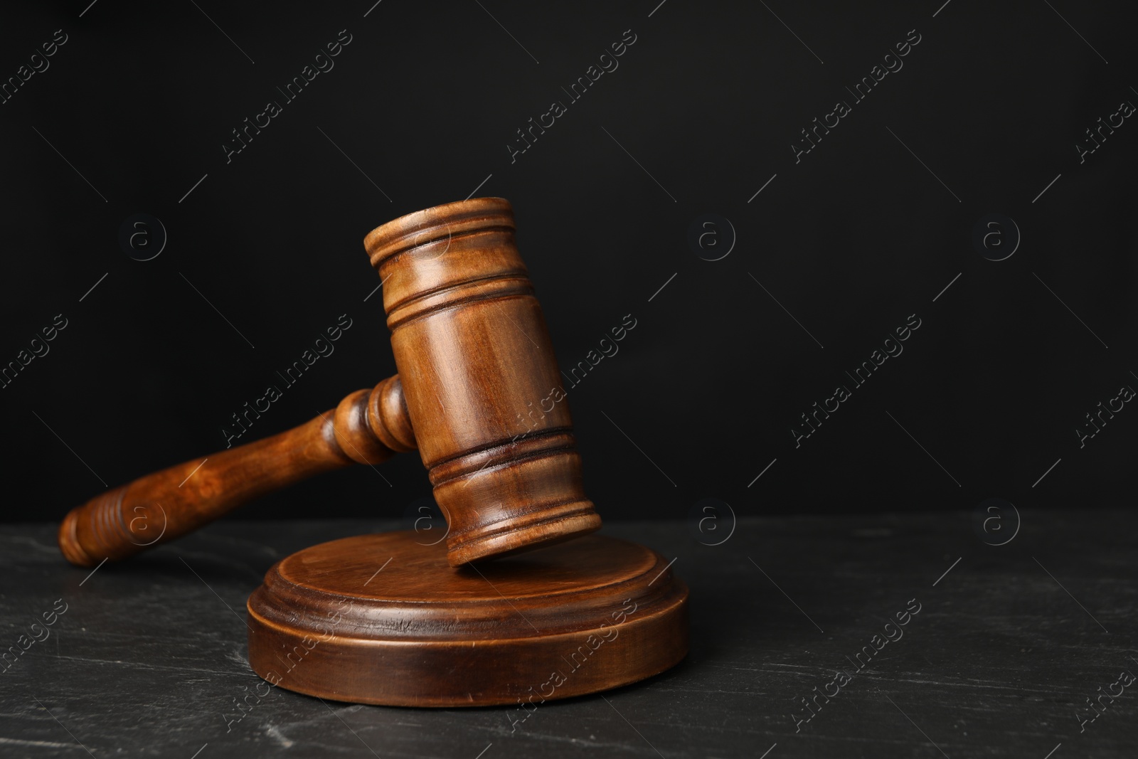 Photo of Wooden gavel on dark textured table, closeup. Space for text