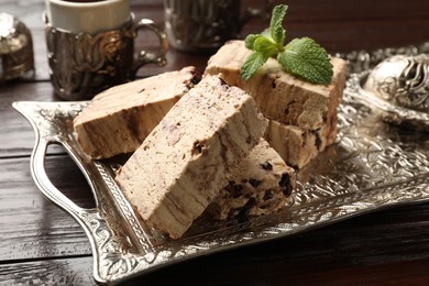 Photo of Tasty chocolate halva and mint on wooden table, closeup