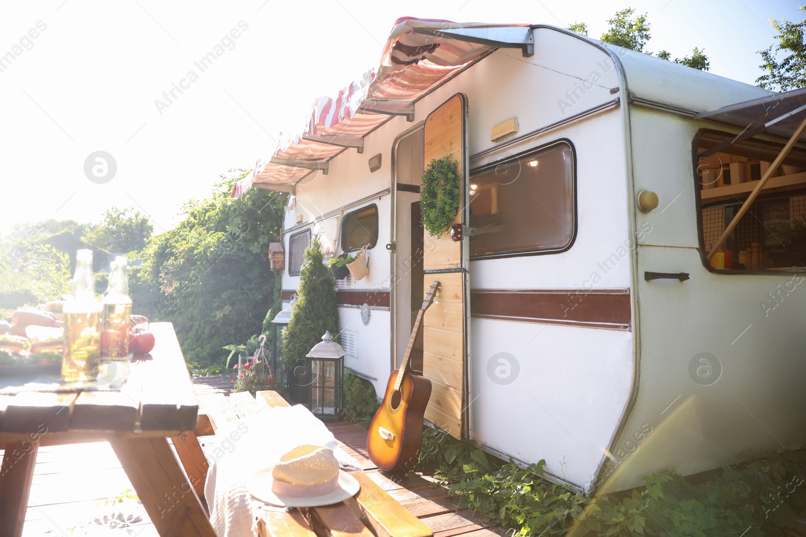 Photo of Guitar near modern trailer on sunny day. Camping season