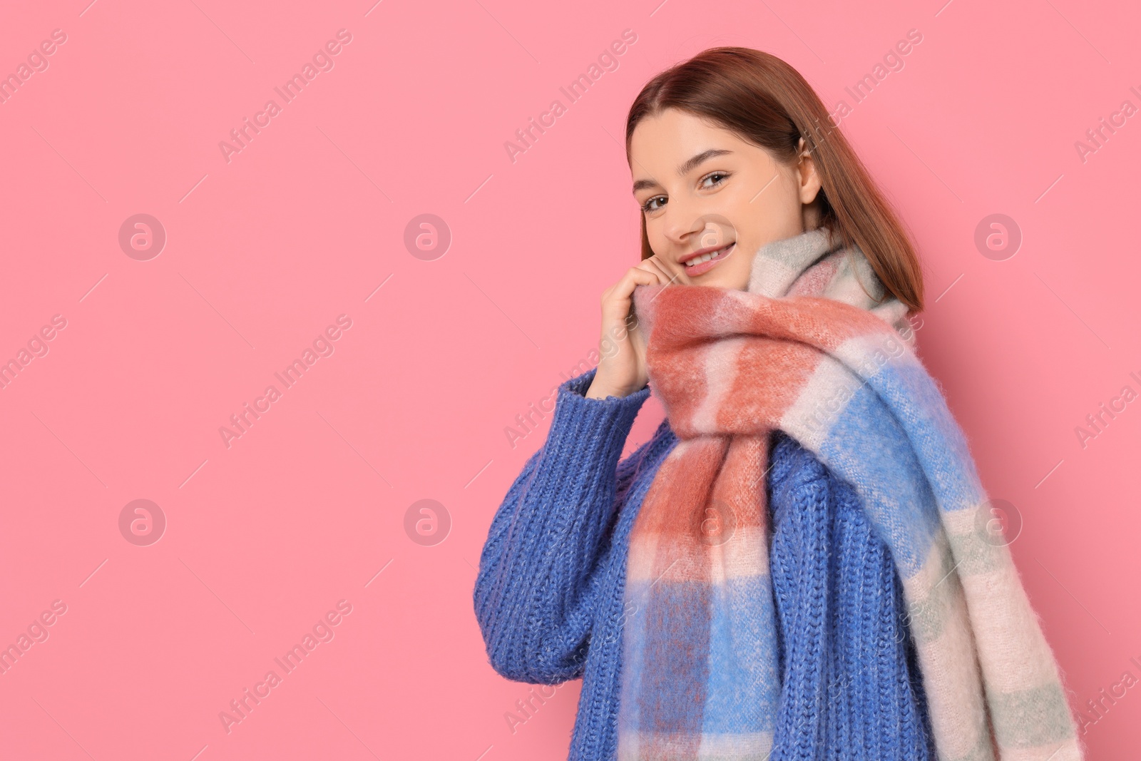 Photo of Beautiful woman in warm scarf on pink background, space for text