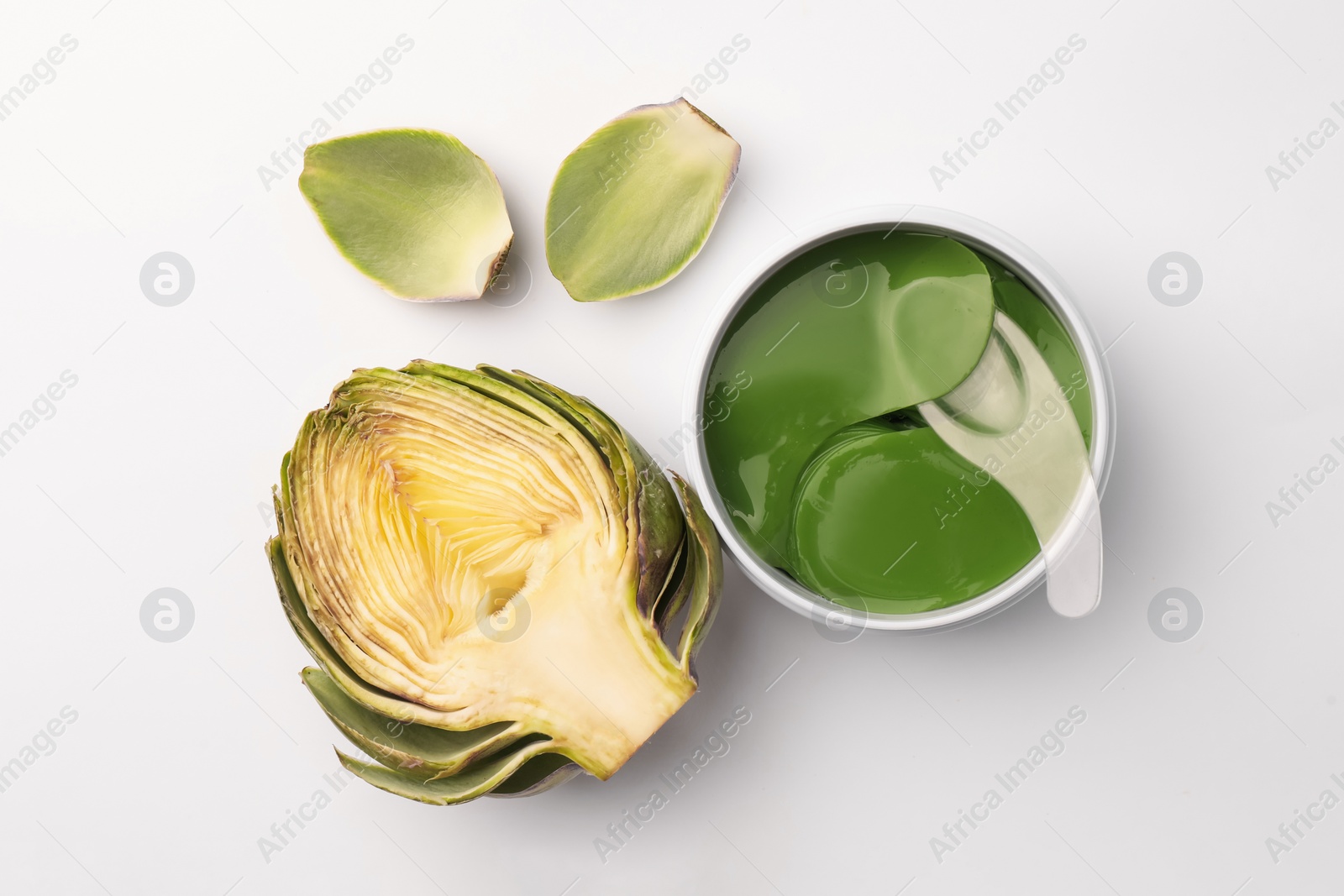 Photo of Package of under eye patches and artichokes on white background, top view. Cosmetic product