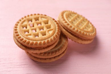 Tasty sandwich cookies with cream on pink wooden table, closeup