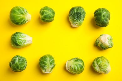 Photo of Fresh Brussels sprouts on yellow background, flat lay. Space for text