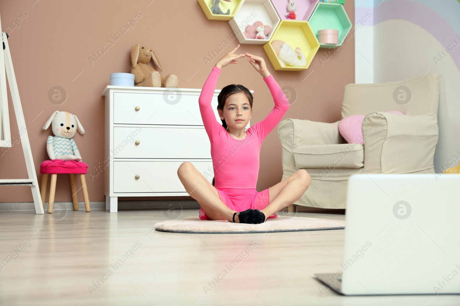 Photo of Cute little girl warming up before online dance class at home