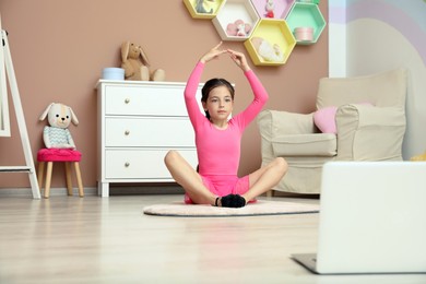 Cute little girl warming up before online dance class at home