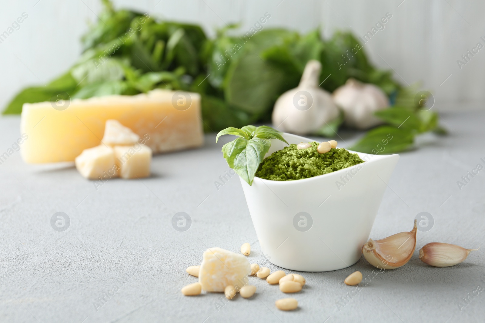 Photo of Composition with bowl of tasty pesto sauce on grey table. Space for text