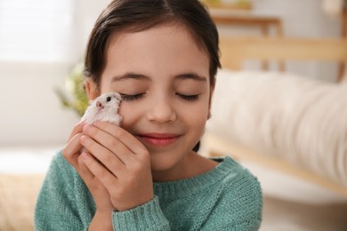 Photo of Little girl with cute hamster at home
