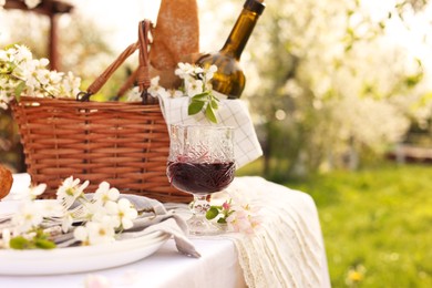 Photo of Stylish table setting with beautiful spring flowers and wine in garden