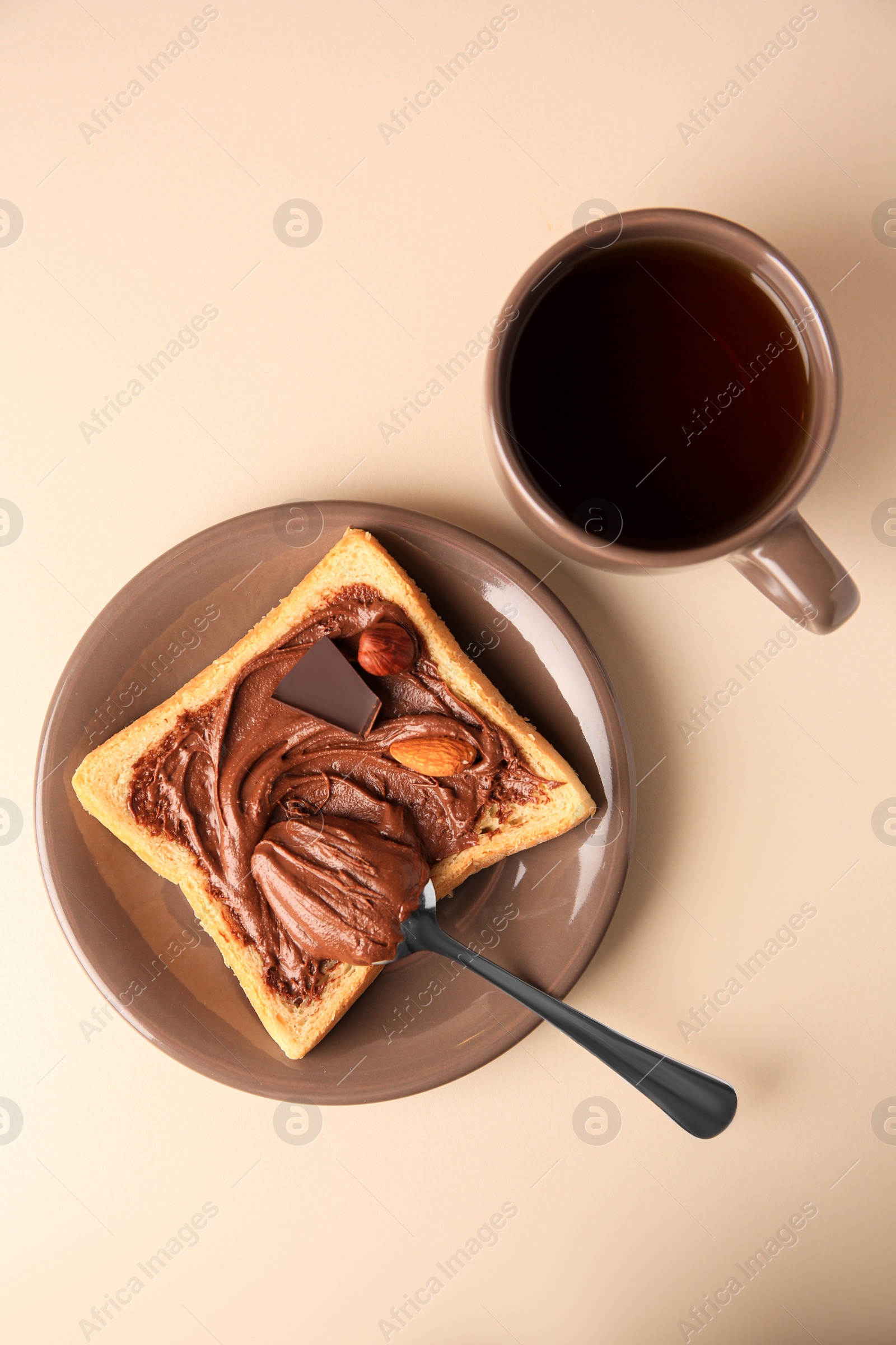 Photo of Tasty toast with chocolate paste and cup of tea served on light table, flat lay