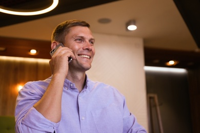 Photo of Happy man talking on smartphone in cafe