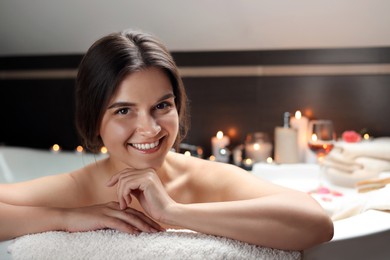 Happy beautiful woman taking bath indoors. Romantic atmosphere