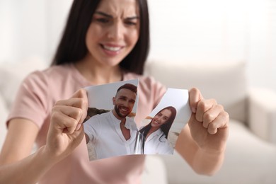 Photo of Upset woman ripping photo at home, selective focus. Divorce concept
