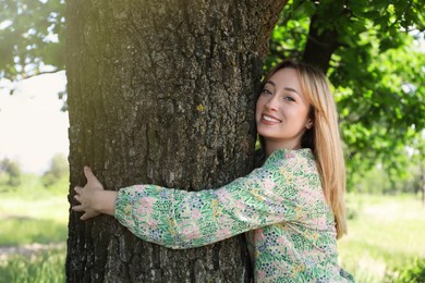 Photo of Beautiful young woman hugging tree trunk in forest
