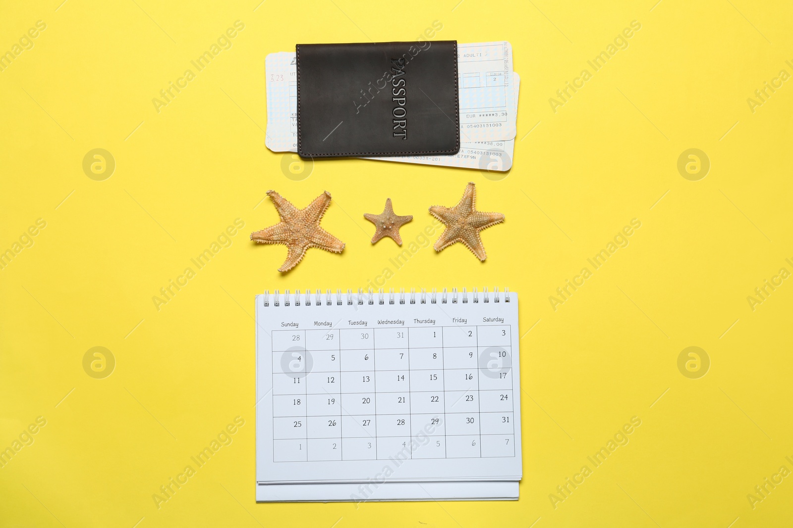 Photo of Passport, tickets and calendar on yellow background, flat lay