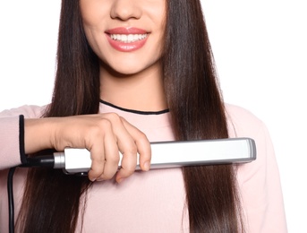 Happy woman using hair iron on white background, closeup