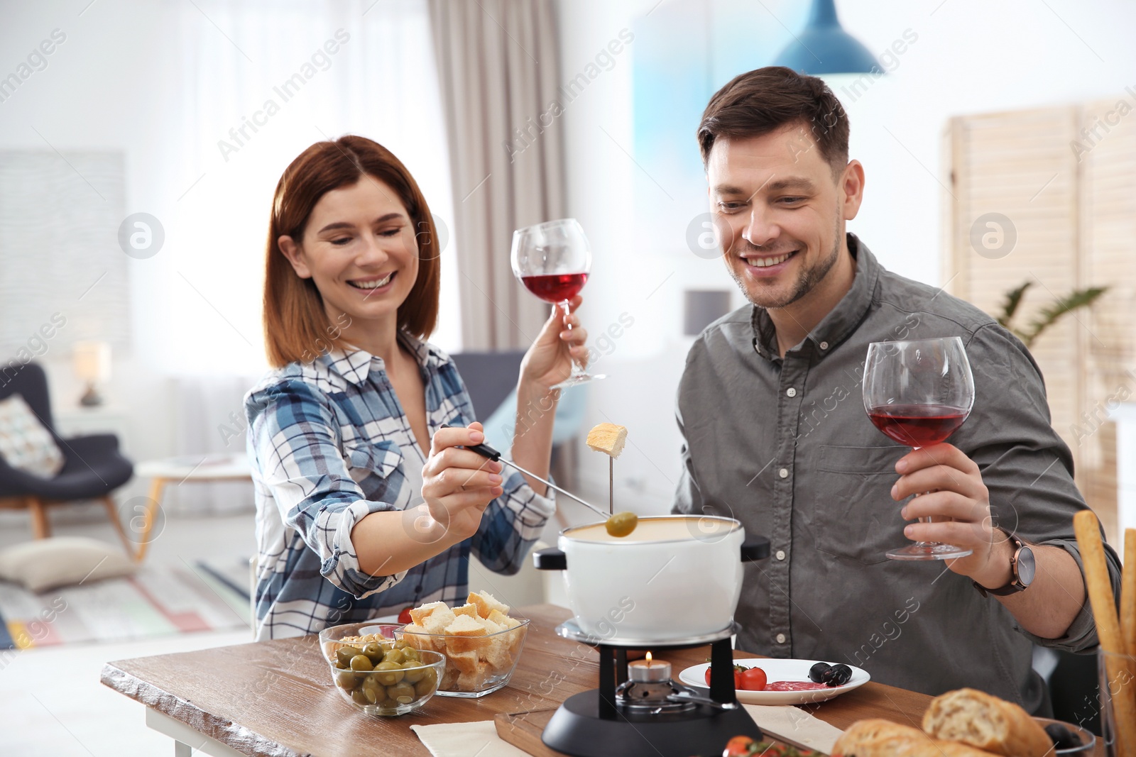 Photo of Happy couple enjoying fondue dinner at home