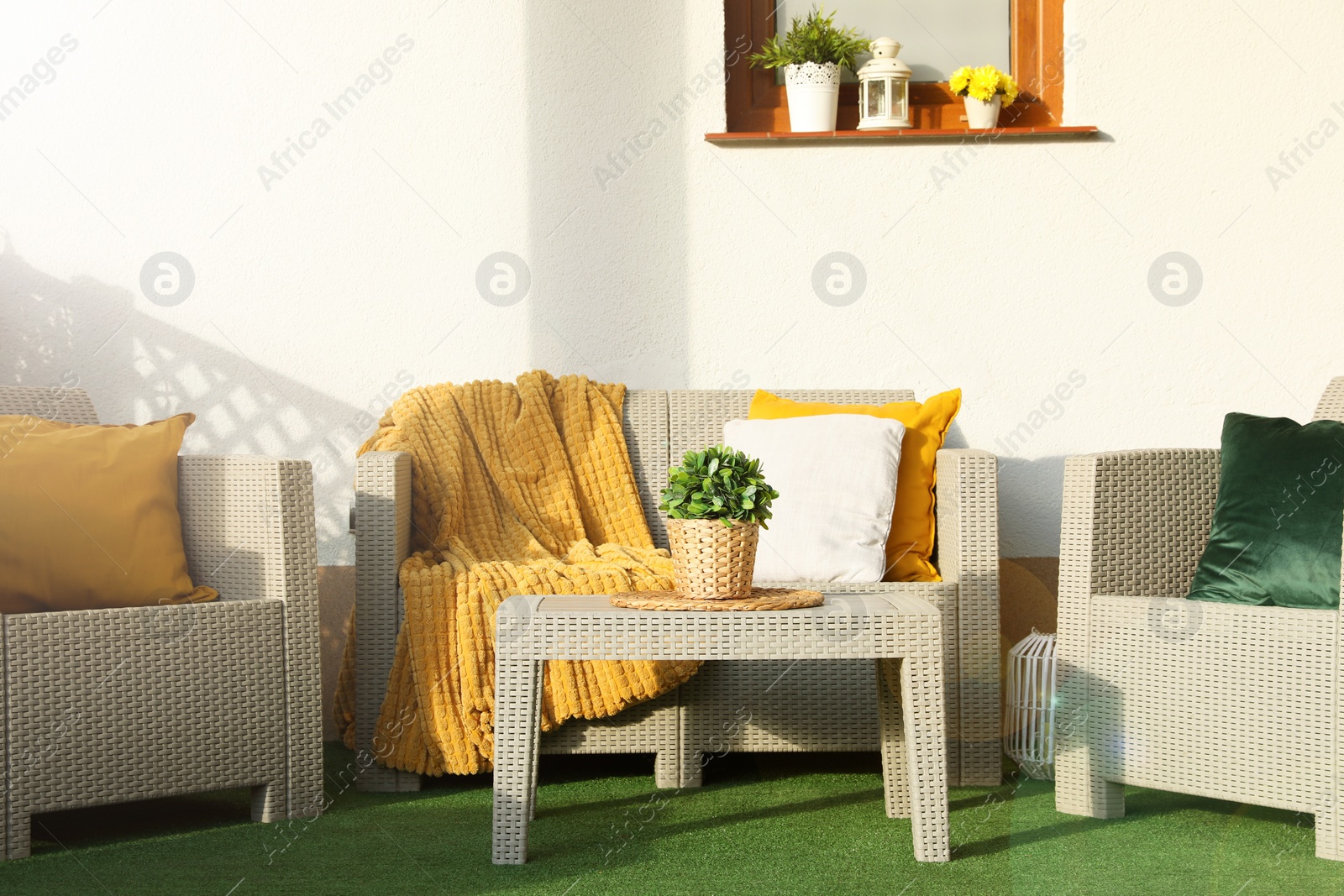 Photo of Beautiful rattan garden furniture, soft pillows, blanket and houseplant outdoors