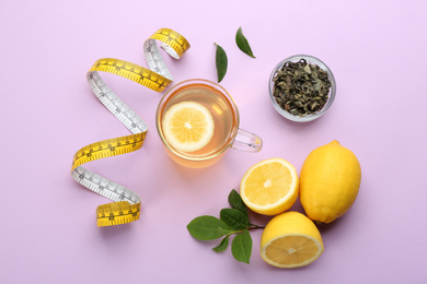 Photo of Flat lay composition with glass cup of diet herbal tea and measuring tape on violet background